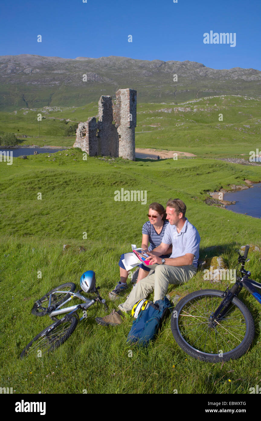 Paar erholsame nach Bikeride neben Ardvreck Castle, Loch Assynt, Großbritannien, Schottland, Sutherland Stockfoto