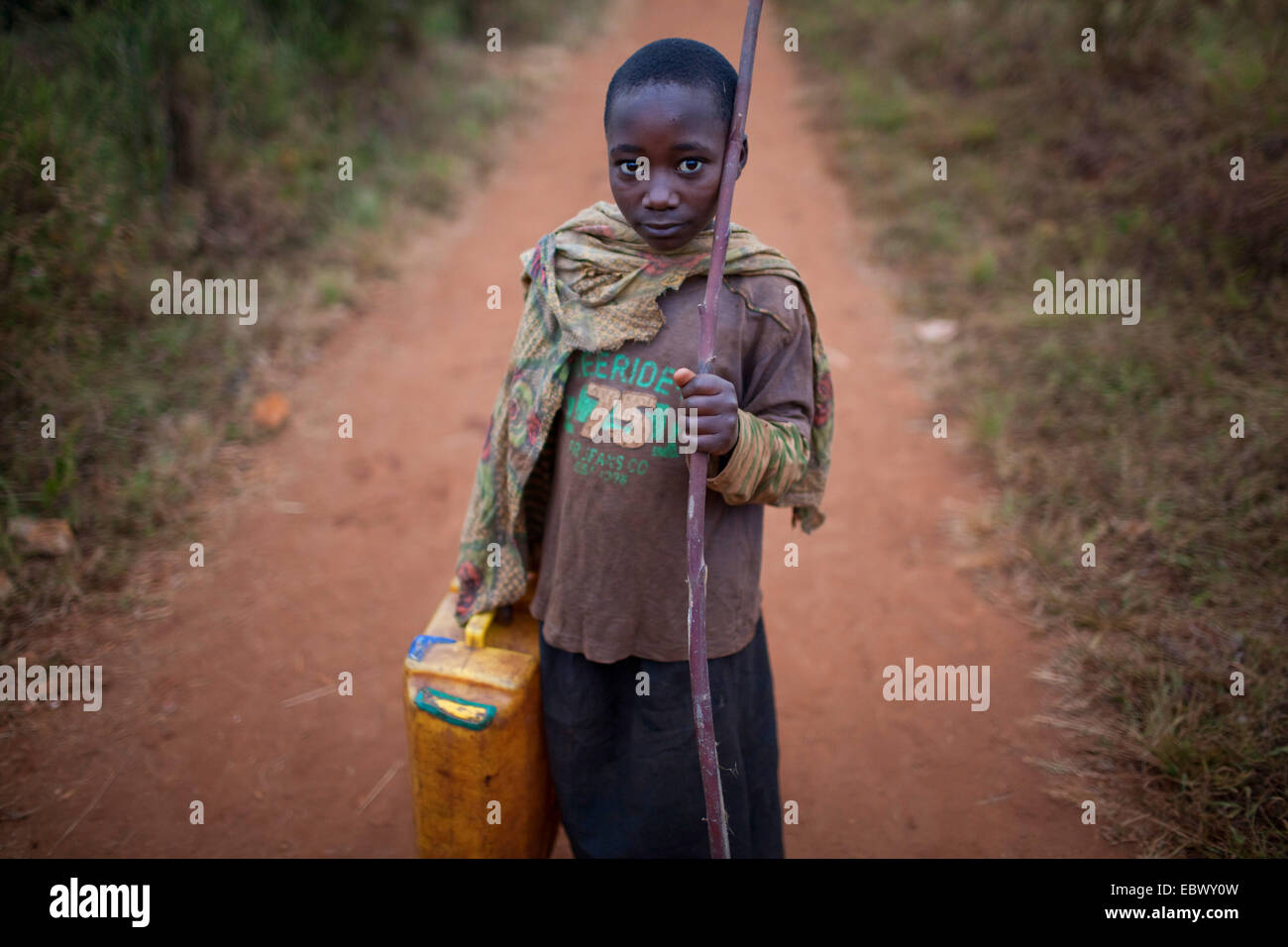 Mädchen stehen mit Wasserkanister und Wanderstock auf staubigen Weg, Burundi, Karuzi, Buhiga Stockfoto