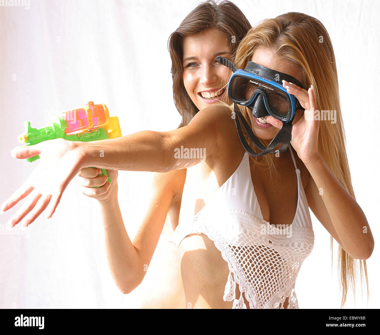 zwei schöne junge Frauen tragen Bikinis herumalbern mit Awater Pistole und Tauchen Brillen Stockfoto