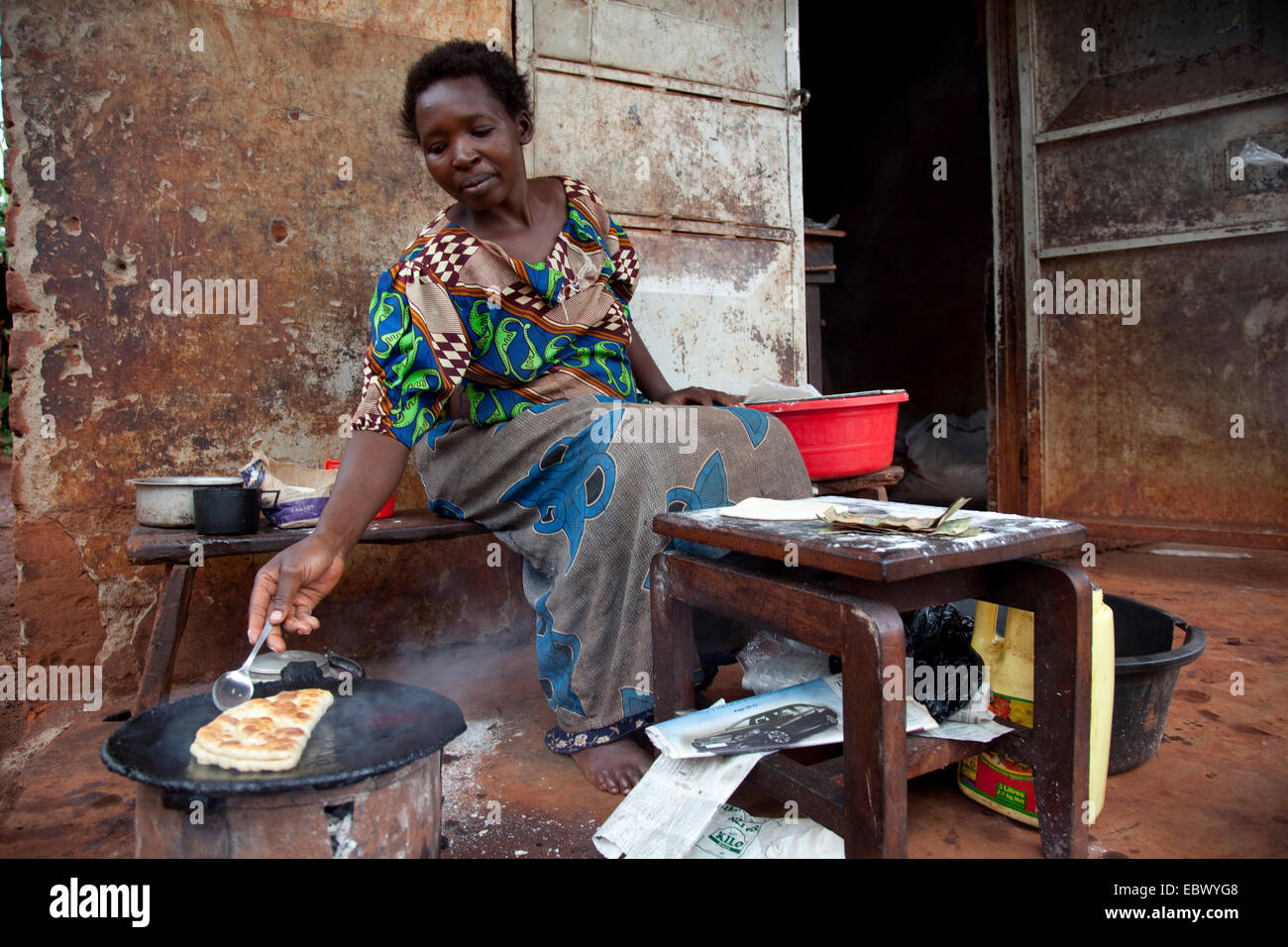 Frau ist ein Chapati gemacht Mais Mehl auf einem Charcole-Ofen vor ein einfaches Haus, Uganda, Jinja genannt Brotbacken Stockfoto