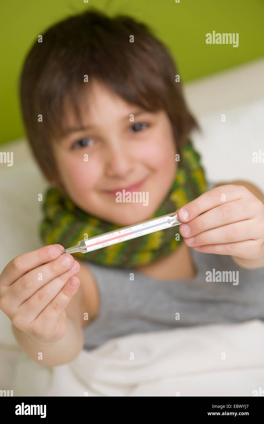 kranker Junge mit Fieberthermometer im Bett liegend Stockfoto