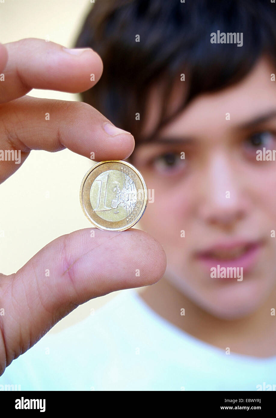 junger Mann eine 1 Euromünze zwischen den Fingern halten Stockfoto