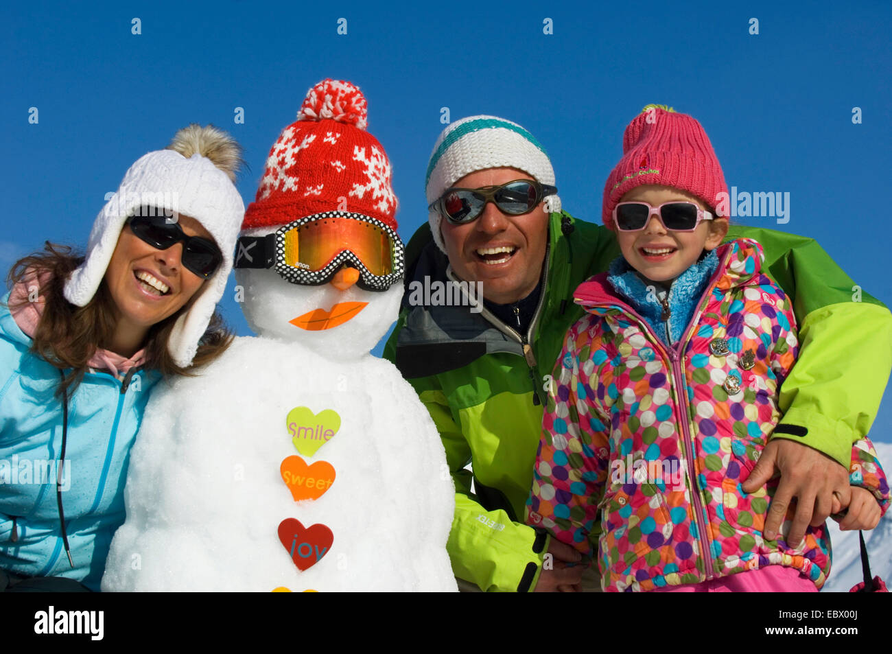 Gruppenfoto der eine Familie mit drei in Winterkleidung mit einem Schneemann in den Ferien in den Bergen, Frankreich Stockfoto
