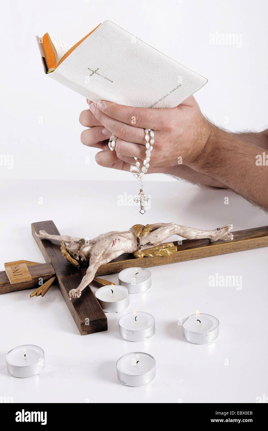 Bibel in der Hand eines Mannes, christliche Dinge auf dem Schreibtisch Stockfoto