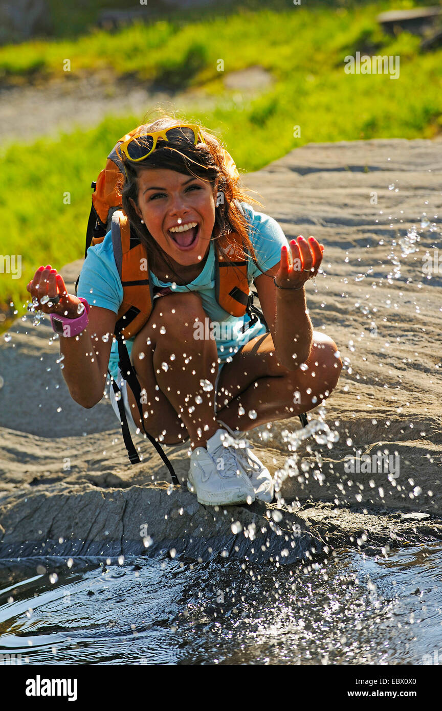 junge Frau spritzt mit Wasser eines Bergsees, Frankreich Stockfoto