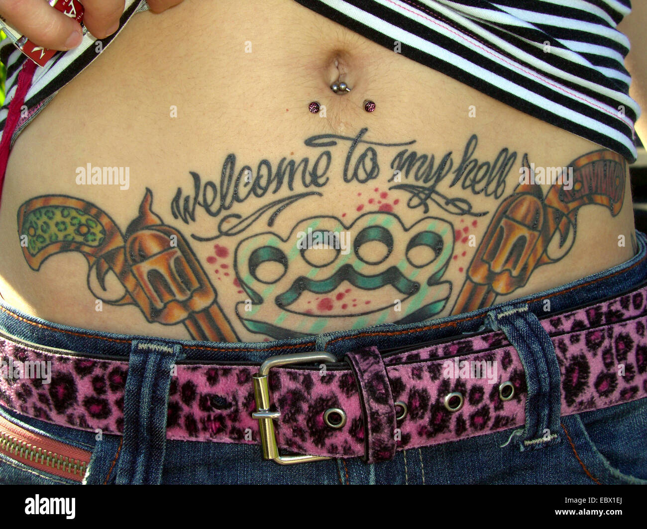 zwei Pistolen und Knuckleduster als Tattoo auf Frau Bauch Stockfoto