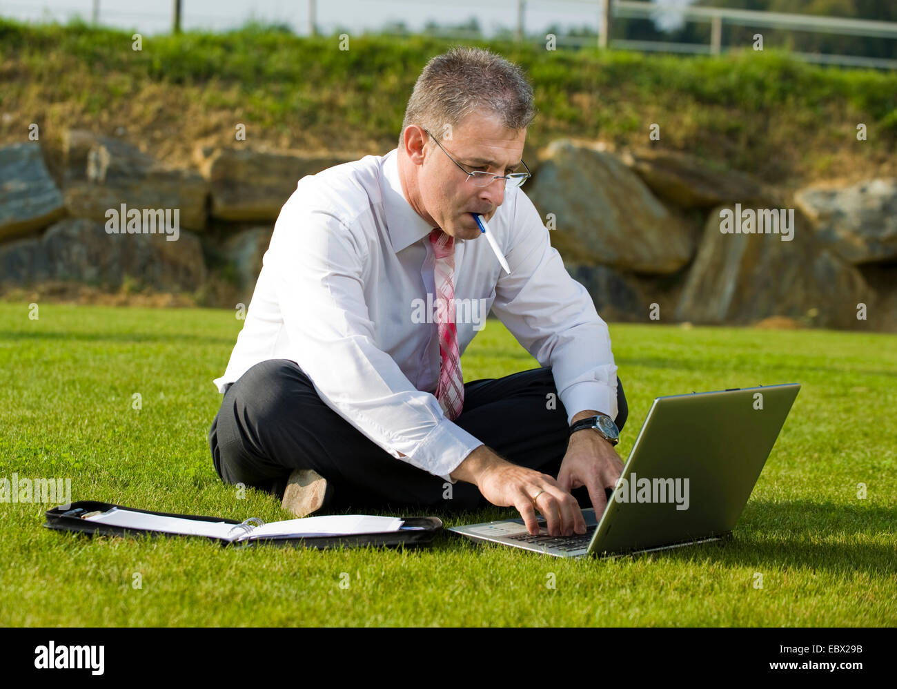 Geschäftsmann, sitzen in der Wiese und mit laptop Stockfoto