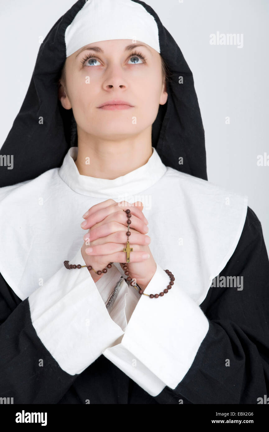 junge Nonne beten den Rosenkranz Stockfoto