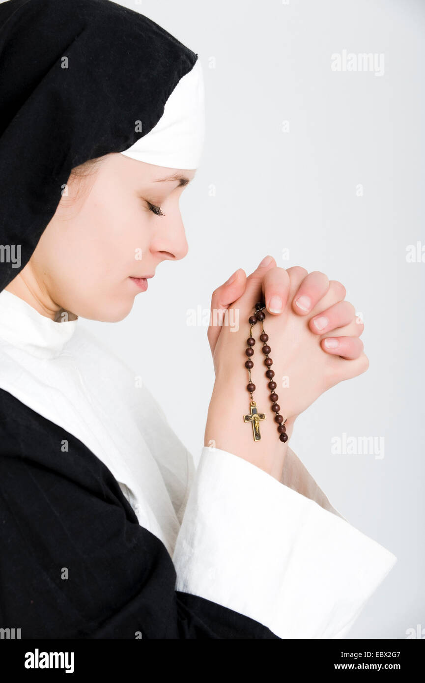 junge Nonne beten den Rosenkranz Stockfoto
