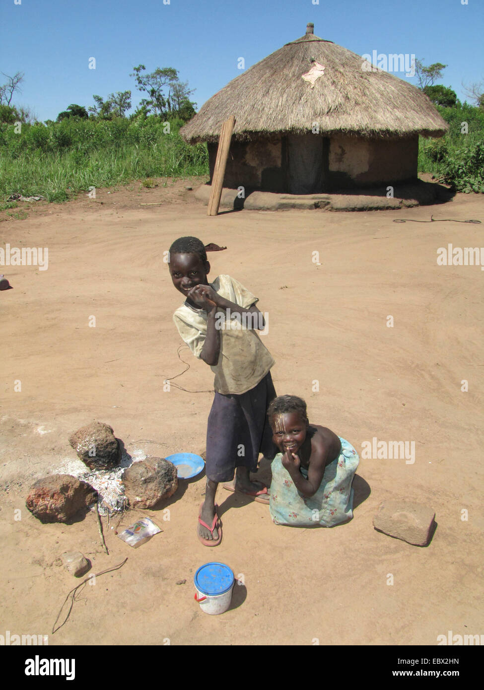 Flüchtlingslager für intern Vertriebene in Nord-Uganda um Gulu, einfachen Lehmhaus im Hintergrund, Kinder spielen am Kamin, Uganda, Gulu Stockfoto