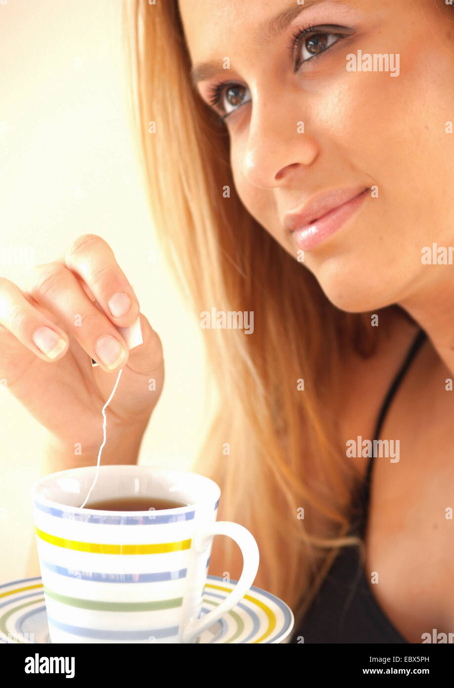 junge Frau strahlt Gelassenheit ist einen Teebeutel in eine Tasse eintauchen. Stockfoto