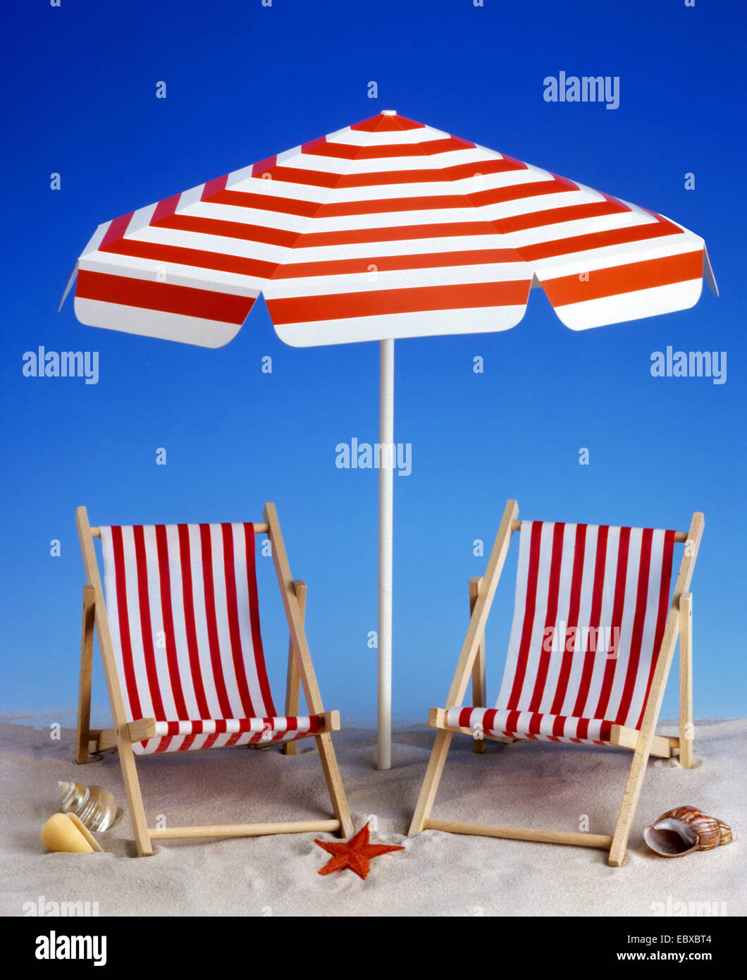 Leinwand Stuhl Miniatur und Sonnenschirm am Sandstrand Stockfoto