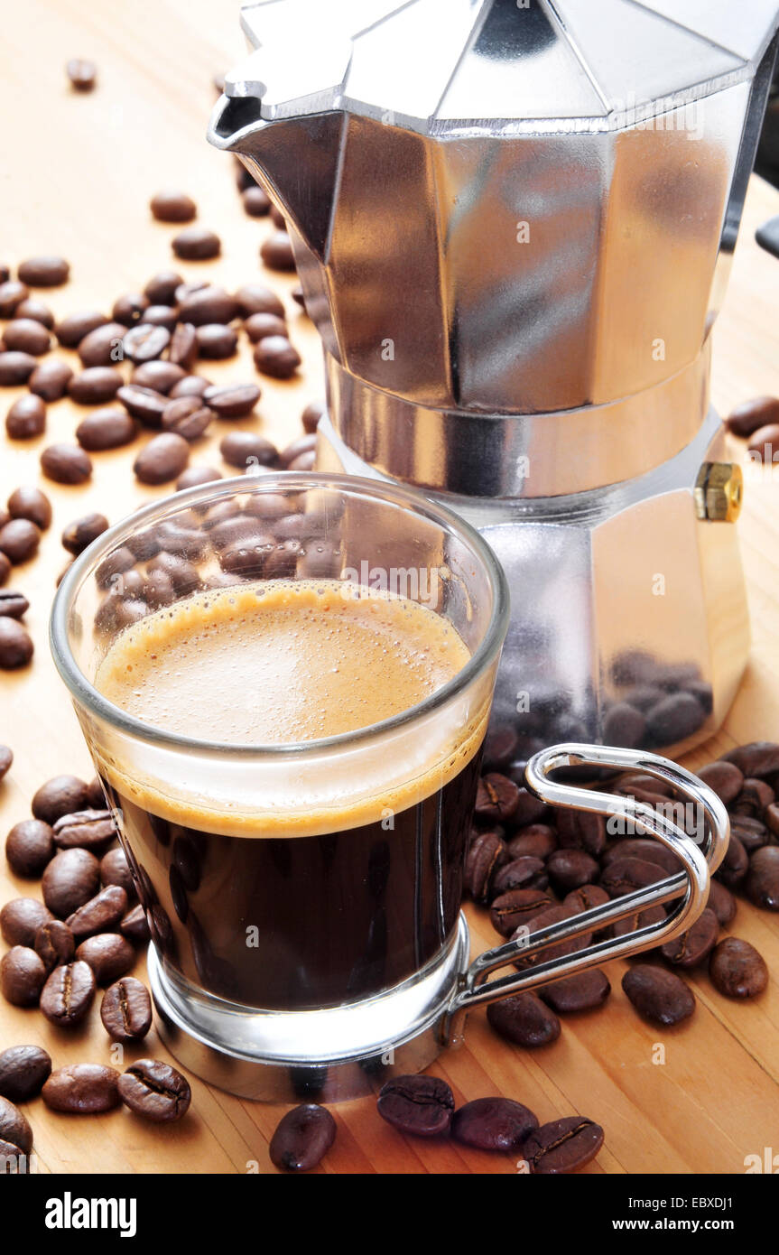 Moka Topf und eine Tasse Kaffee auf einem Holztisch mit gerösteten Kaffeebohnen Stockfoto