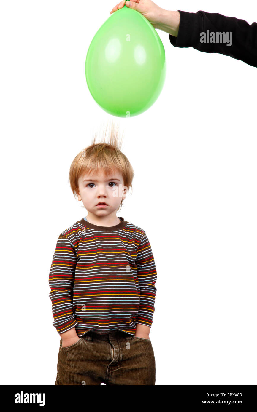 kleiner Junge Haar wird von einem Luftballon angezogen mit statischer Elektrizität aufgeladen Stockfoto