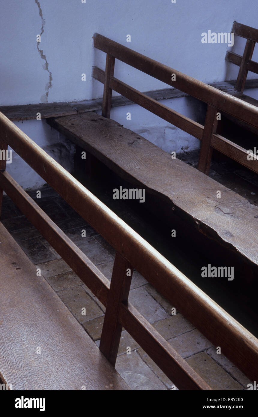 Detail der drei Reihen von einfachen Holzbänken mit Rücken an die Wand in der Schule oder Kapelle oder Kirche befestigt Stockfoto