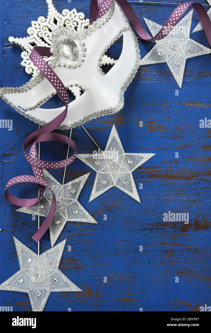 Glückliches Neujahr Hintergrund mit weißen Maskerade Maske und Star Partydekoration auf dunklem Blau rustikal distressed Vintage Holz. Stockfoto