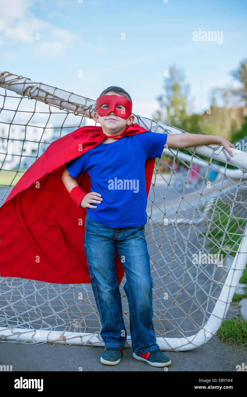 Junge gekleidet in Cape und Maske, stützte sich auf Fußballtor Stockfoto