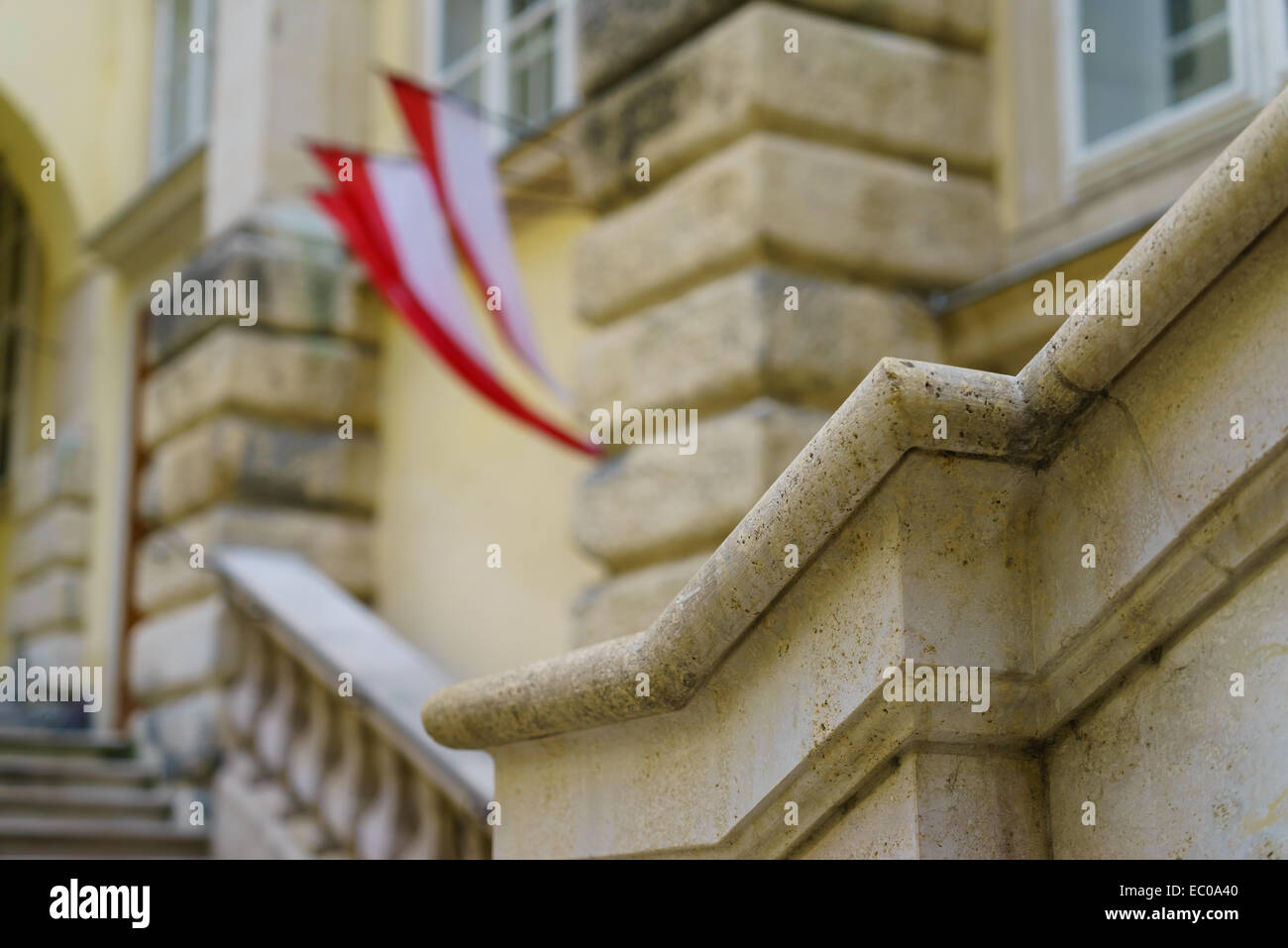 Rote und weiße österreichische Fahne hängen neben steinernen Stufen und eine Tür in der Hofburg Vienna. Stockfoto