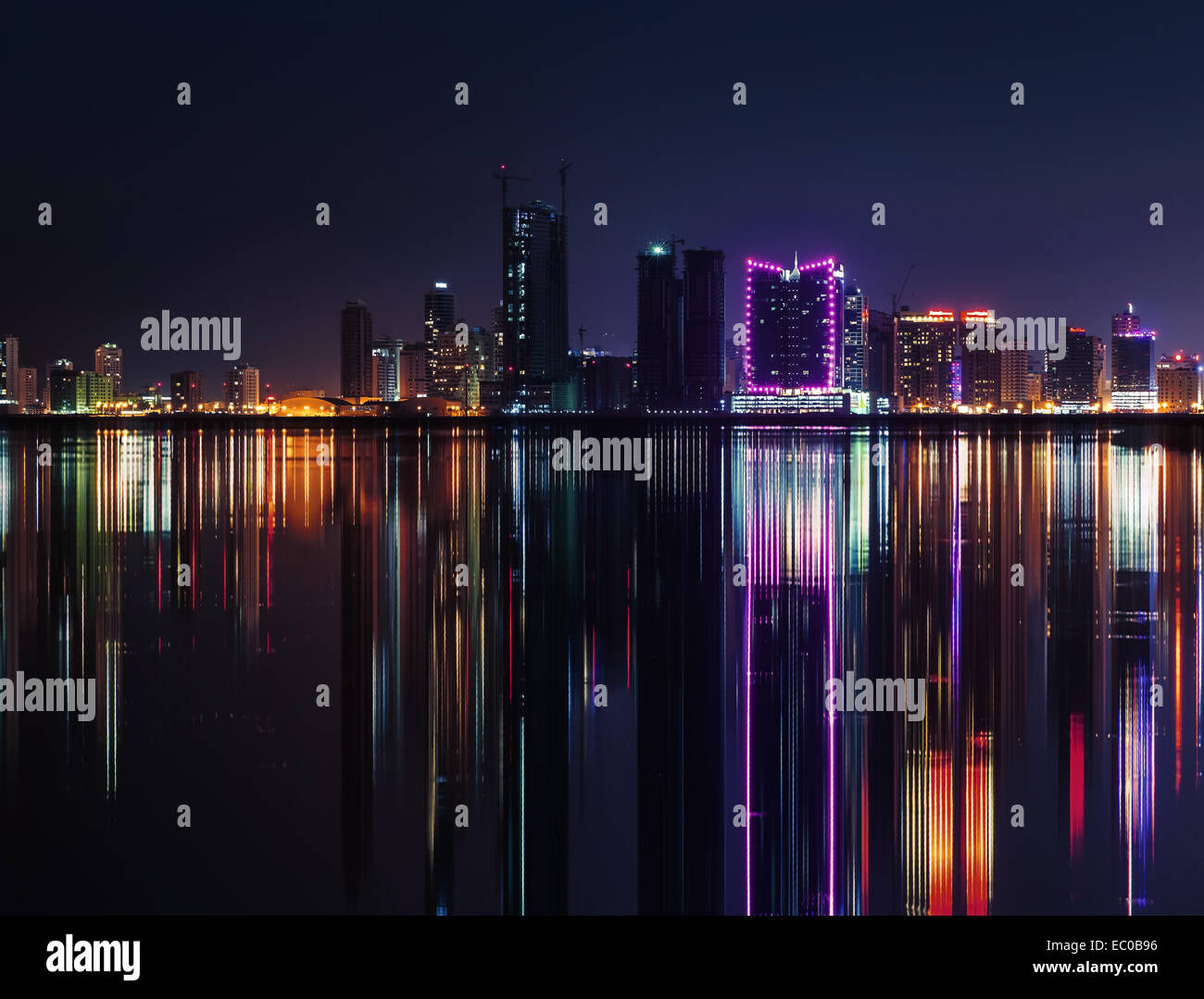 Nacht Skyline der modernen Stadt mit leuchtenden Neonröhren und Spiegelbild im Wasser. Manama, der Hauptstadt von Bahrain, Naher Osten Stockfoto