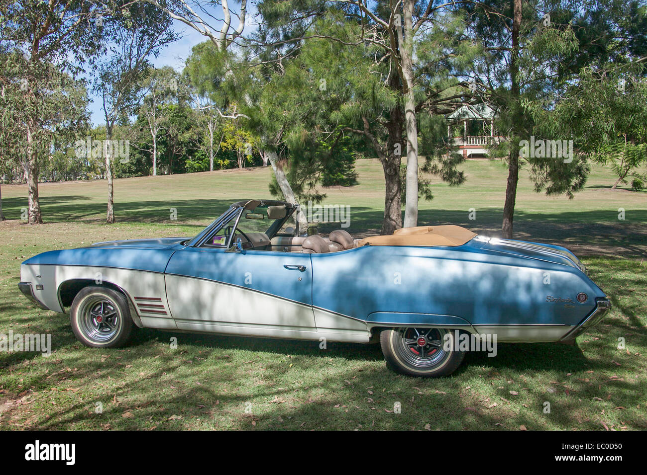 Amerikanische Oldtimer, blau & weiße Cabrio 2-türig Buick Skylark in neuwertigem Zustand mit Kapuze unten auf Rasen durch die Schatten der Bäume Stockfoto