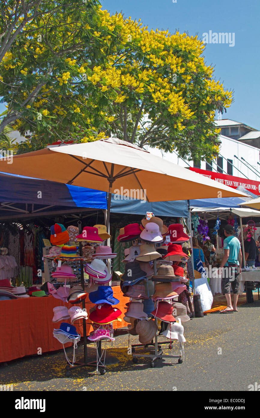 Bunte Hüte zum Verkauf unter Sonnensegels & Blütenbaum am Stand am Wochenmarkt in der Stadt von Maryborough Queensland Stockfoto