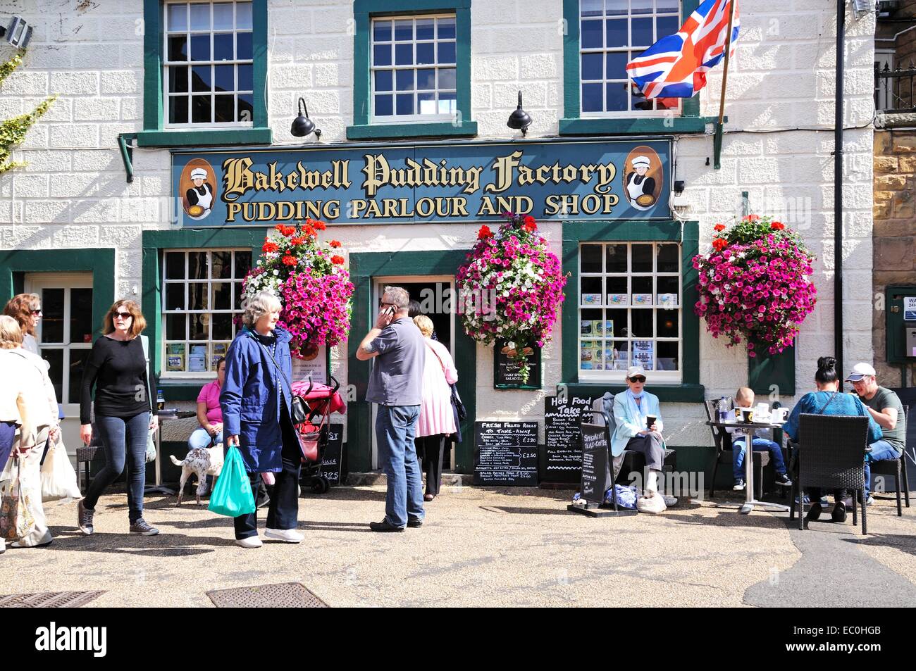 Touristen sitzen in einem Straßencafé außerhalb der Bakewell Pudding Fabrik im Zentrum Stadt, Bakewell, Derbyshire, England, Vereinigtes Königreich, Stockfoto