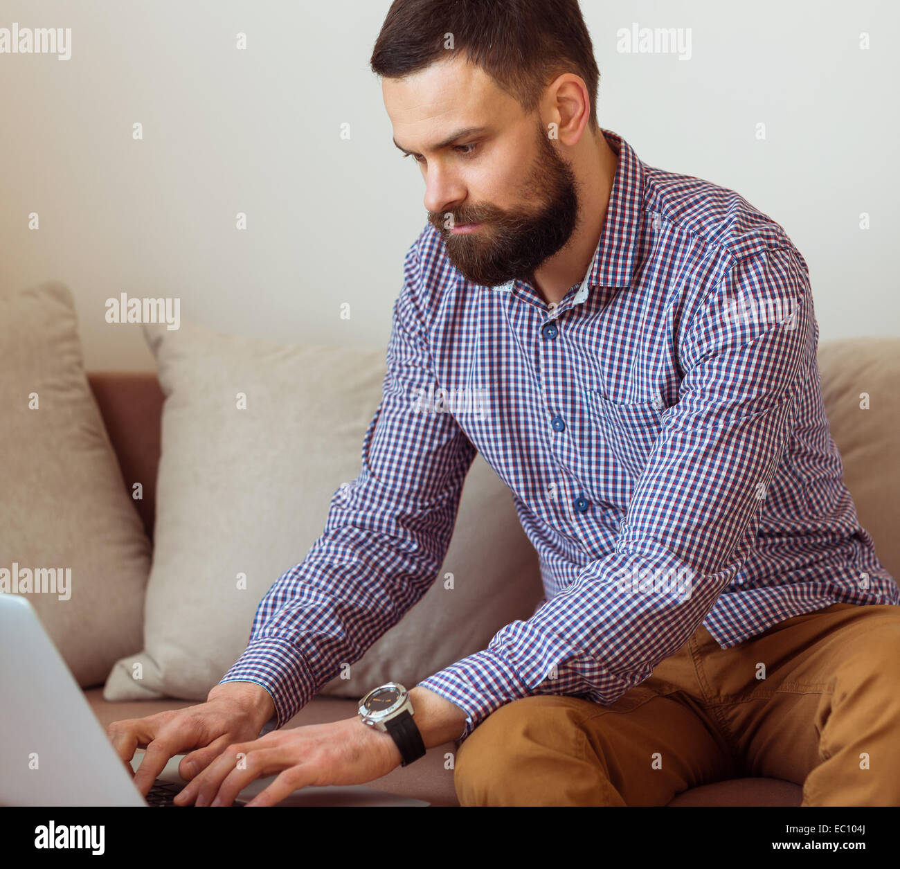 Junge bärtige Mann arbeitet am Laptop zu Hause Stockfoto