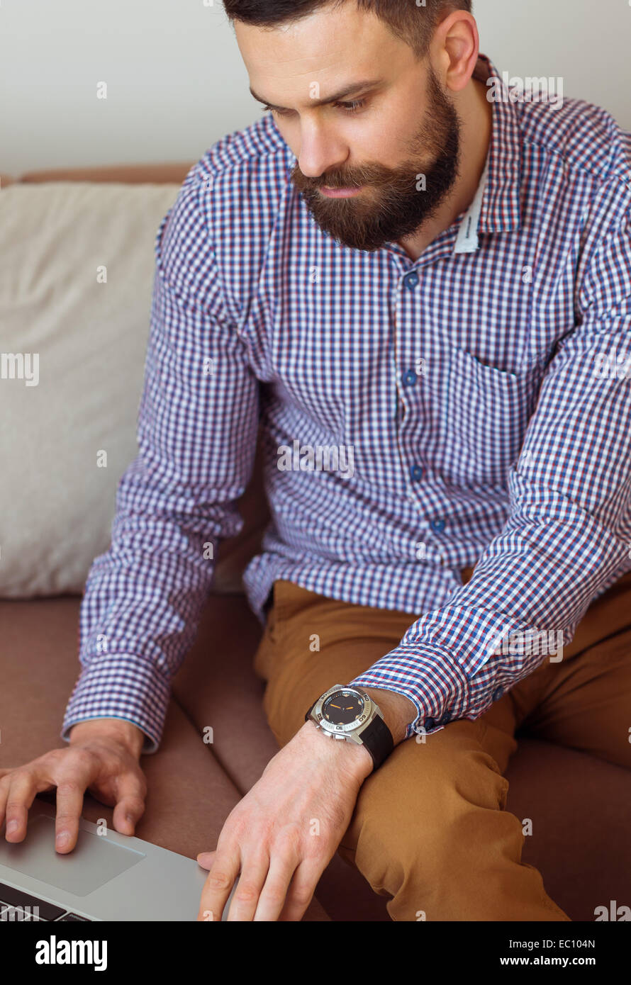 Junge bärtige Mann arbeitet am Laptop zu Hause Stockfoto