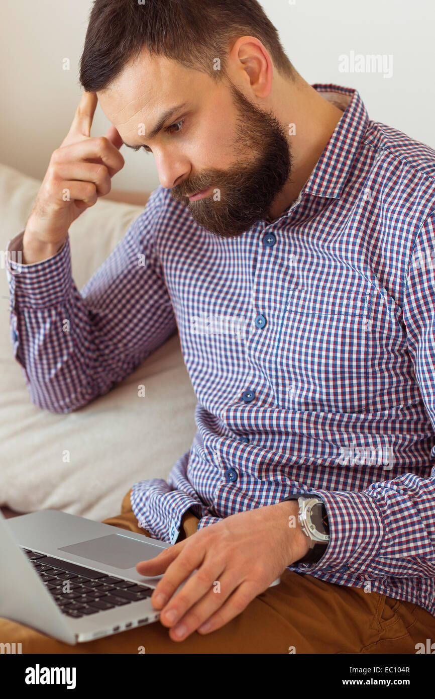Junge bärtige Mann arbeitet am Laptop zu Hause Stockfoto