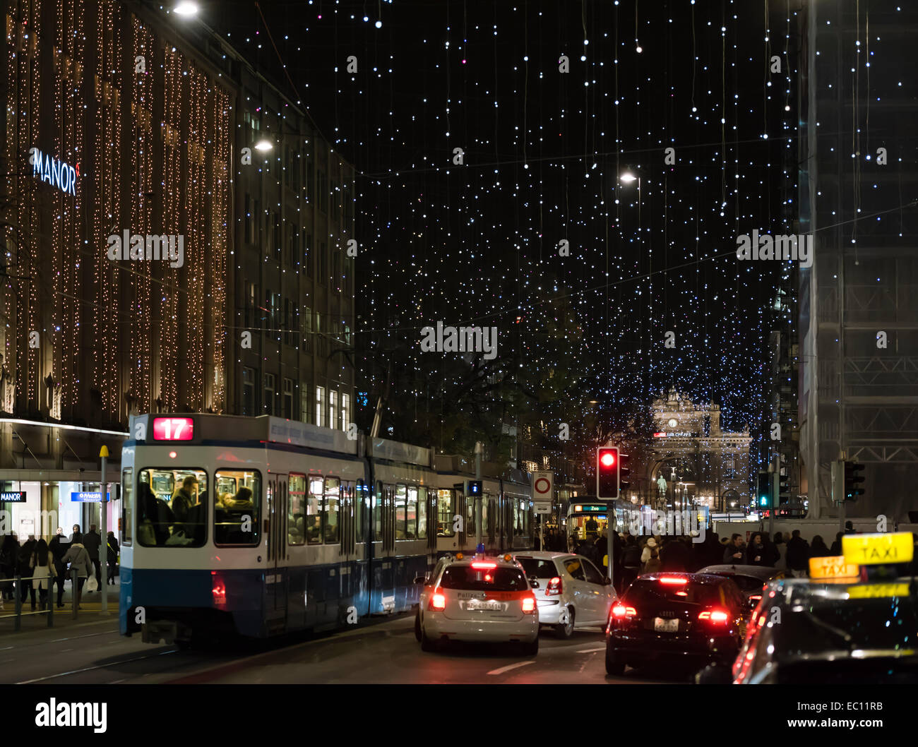 Weihnachts-Einkäufer, Autos und Straßenbahn-Zügen im Zürcher überfüllt Bahnhofstrasse unter der glühenden Weihnachtsbeleuchtung Stockfoto