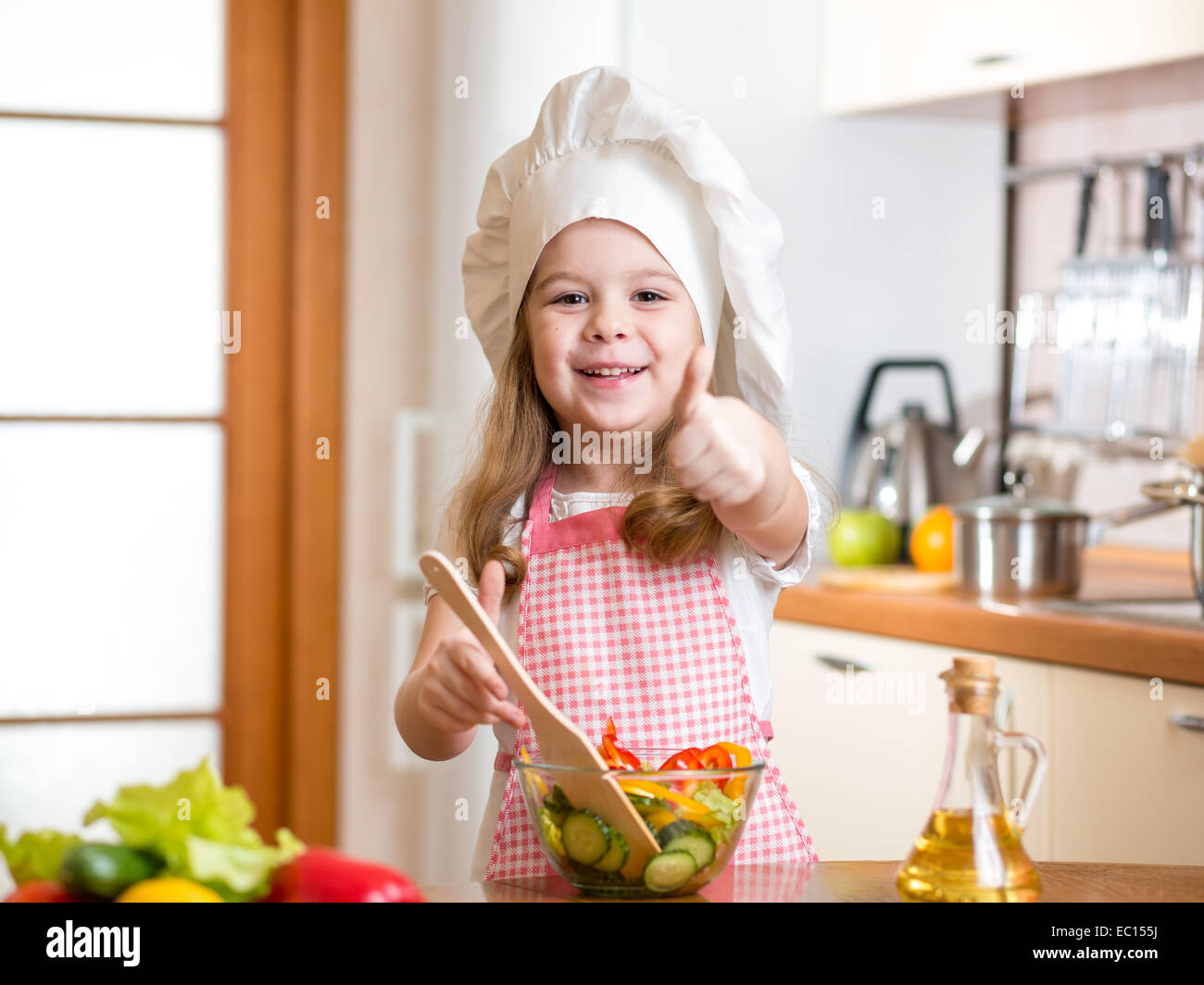 Kind Mädchen Essen zubereiten und Daumen auftauchen Stockfoto
