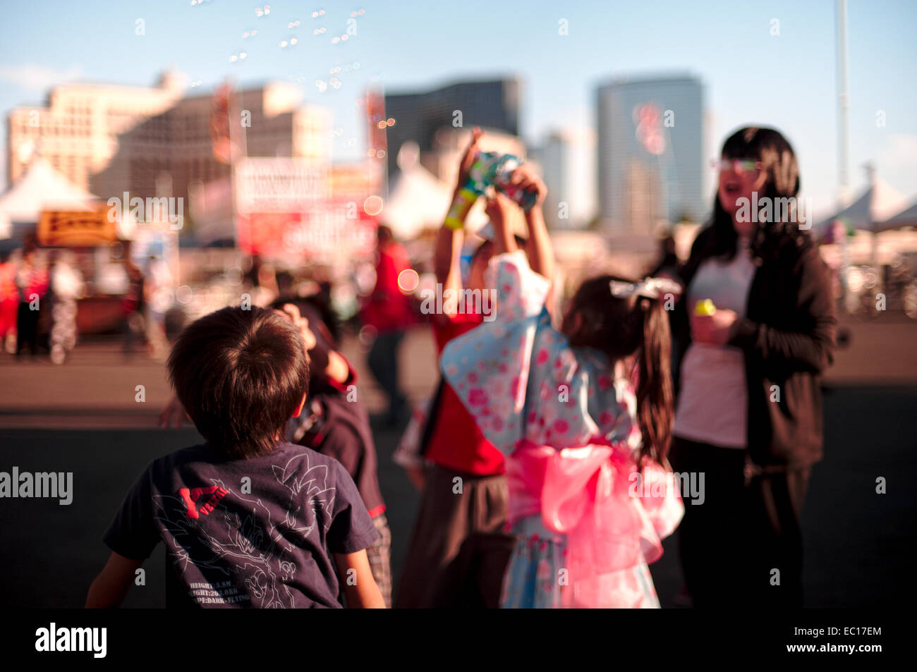 Ein junges Mädchen, gekleidet in traditionellen japanischen Festival Verschleiß (Yukata) hält eine fischförmige Blase bläst Spielzeug wie andere Kinder Stockfoto