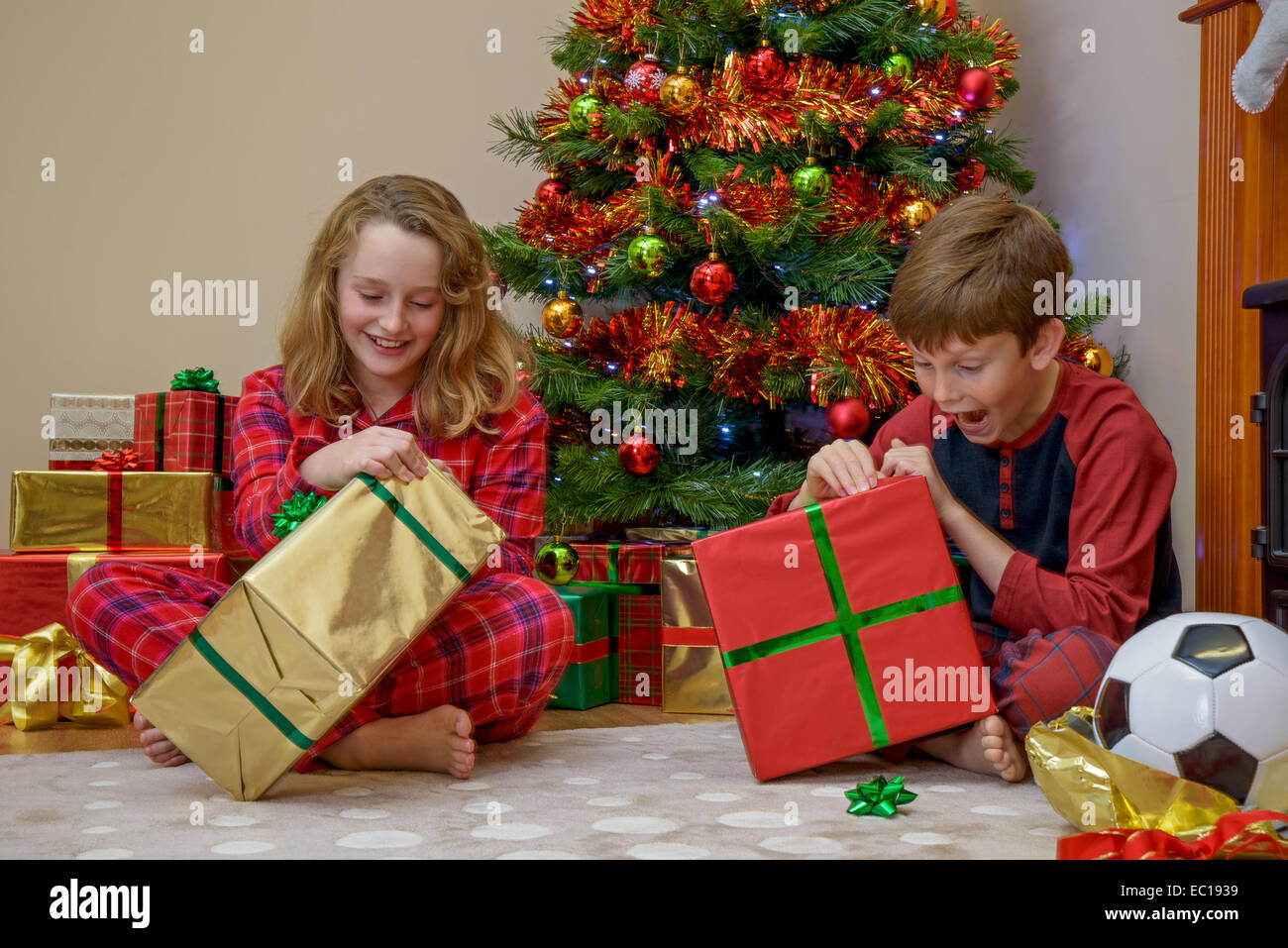 Zwei Kinder, ein Junge und ein Mädchen, das ihre Geschenke an Weihnachten Morgen. Stockfoto