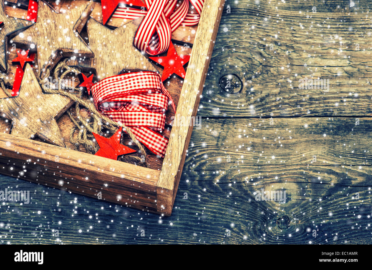 Weihnachtssterne Dekorationen aus Holz und roten Bändern auf rustikalen hölzernen Hintergrund. Vintage-Stil getönten Bild mit fallenden Schnee ef Stockfoto