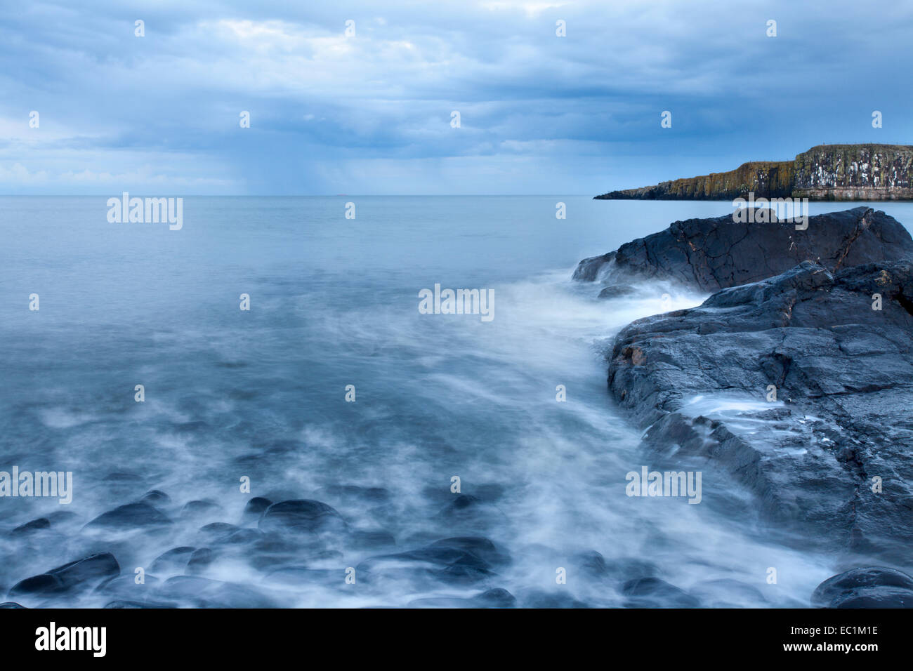 Regen über dem Meer an der Greymare Felsenküste Dunstanburgh Northumberland in England Stockfoto
