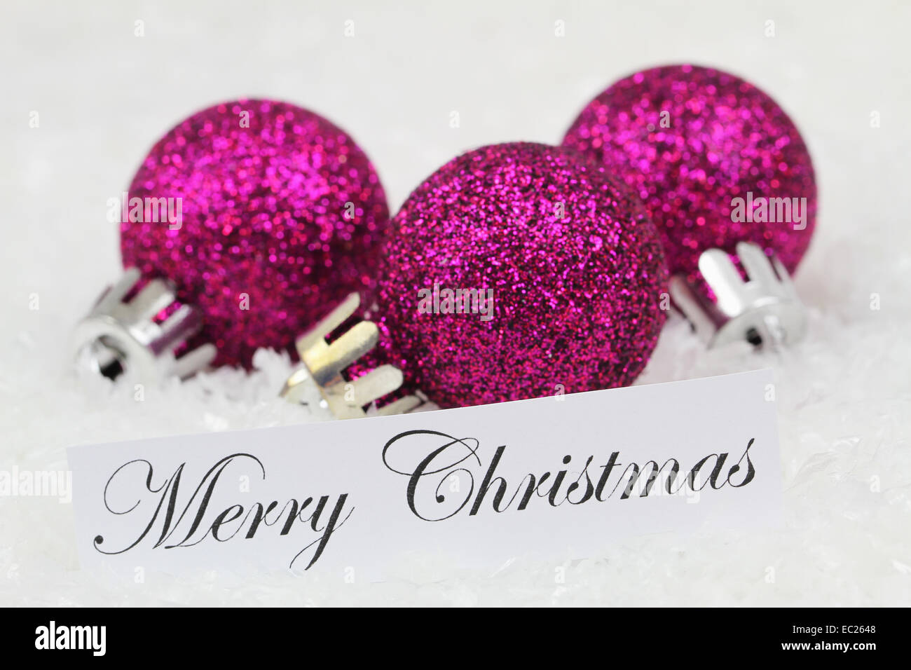 Lustige Weihnachtskarte mit lila Kugeln auf Schnee Stockfoto
