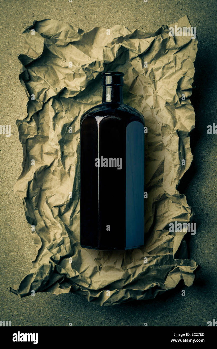 Schwarzglas achteckige Flasche auf ein zerknittertes Papierhintergrund. Stockfoto