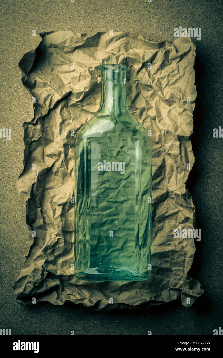 Blaue grüne Glasflasche auf ein zerknittertes Papierhintergrund. Stockfoto