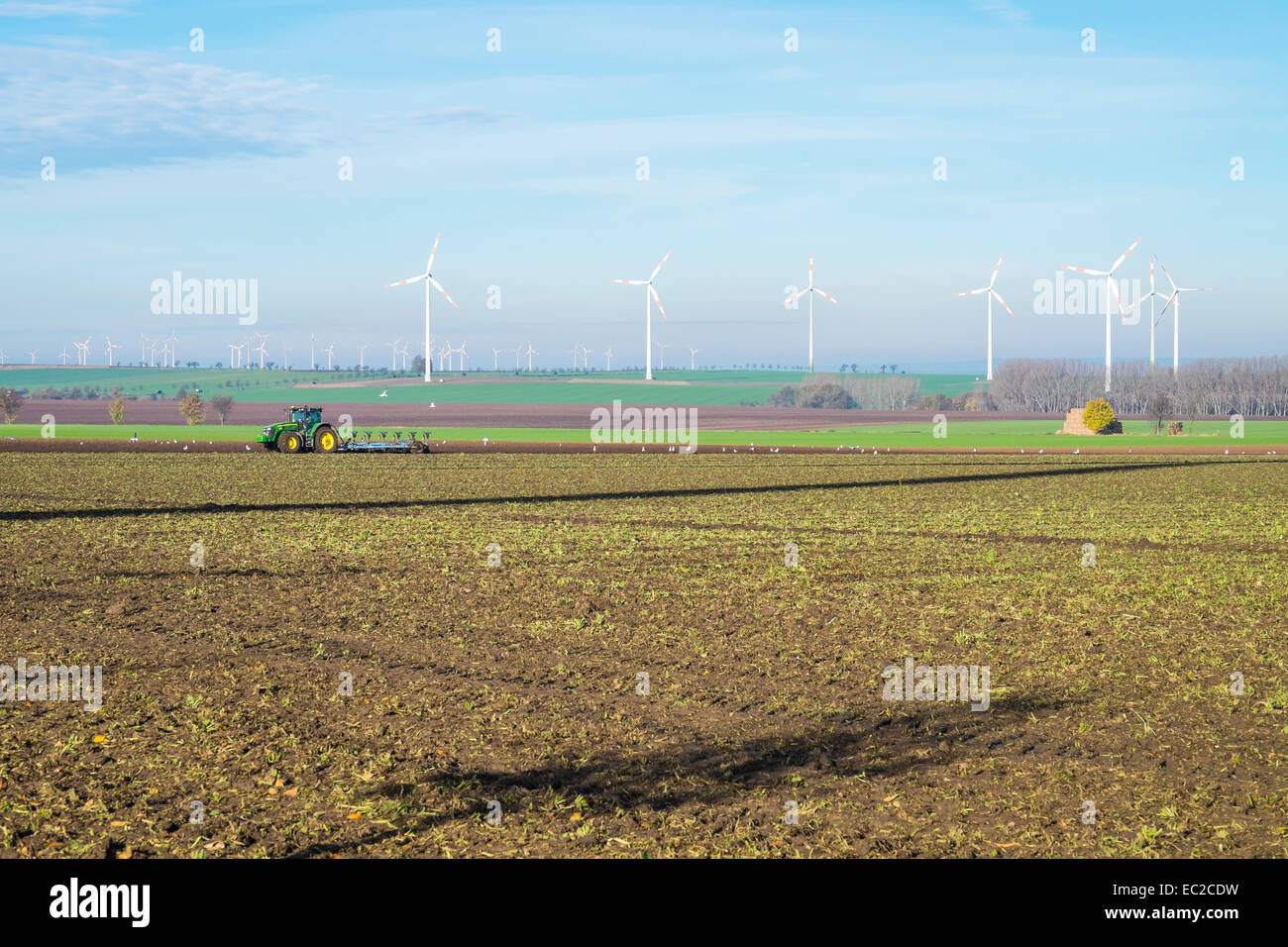 Landwirtschaft und Energie Industrie - Traktor Pflügen der Felder mit einem Windpark in Sachsen-Anhalt, Manfelder Land geteilt Stockfoto