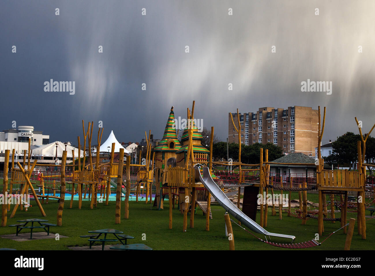 Jungle Jim Spielplatz, Tolkien stil Holz play zone Teil des renovierten Könige Gärten, in einer Parklandschaft, Southport, Merseyside, UKVirga mit Fallen - Streifen von Fallen, nimbostratus Winter Wetter Wolkenformationen. Virga ist eine wahrnehmbare Streifen oder die Welle der Niederschläge fallen von einer Wolke, sondern verdunsten oder subliming, bevor sie den Boden erreicht. Nach dem Gewitter, und der Beginn einer Kaltfront in den frühen Stunden, dem Seebad hält Wind, Schnee, Regen, Regen und Hagel, mit zeitweiligem Sonnenschein. Stockfoto
