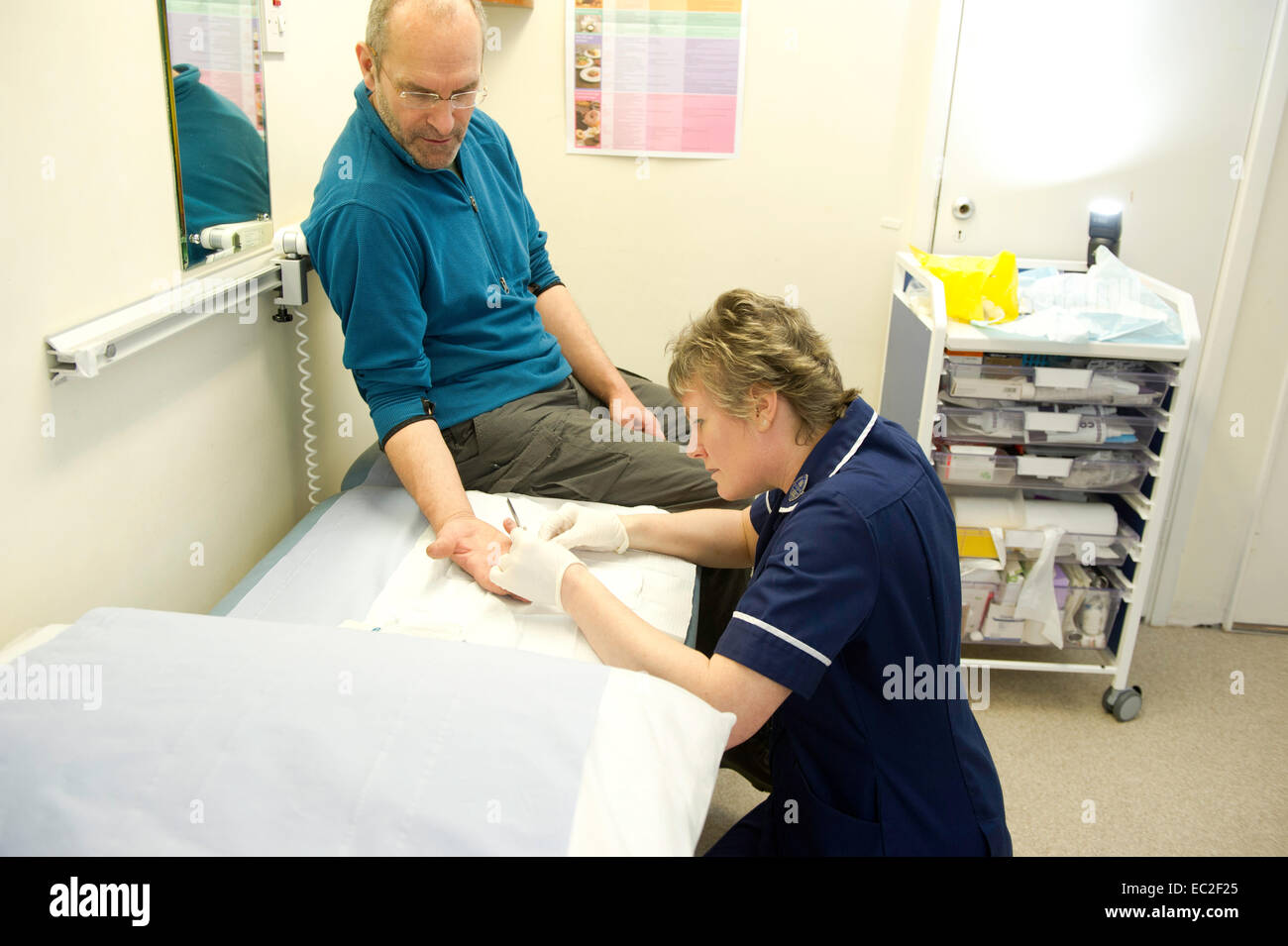 Eine Krankenschwester, die Teilnahme an einem Patienten in einer Klinik NHS Stockfoto