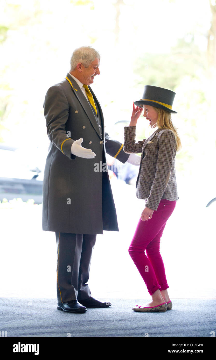 Ein junges Mädchen stiehlt einen Hut von einem concierge Stockfoto