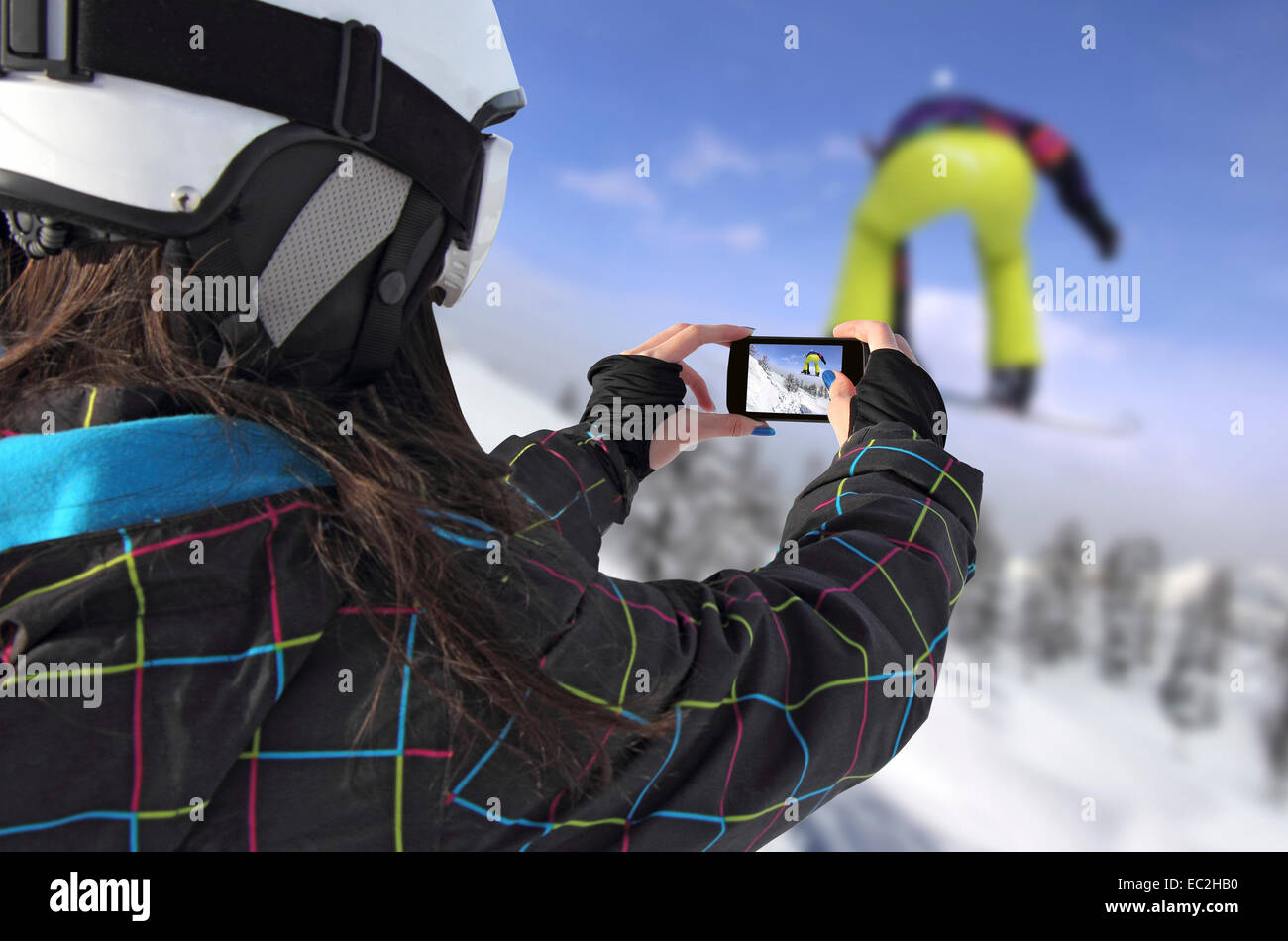 Ein junges Mädchen mit dem Handy fotografiert von Snowboarder springen Stockfoto