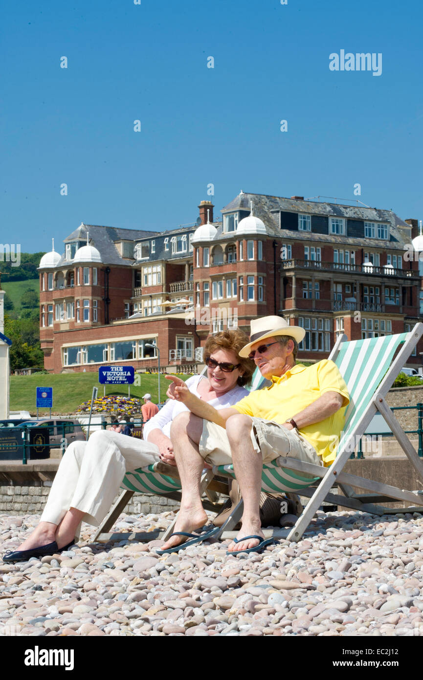 Ein älteres Ehepaar saß auf den Liegestühlen am Strand Stockfoto