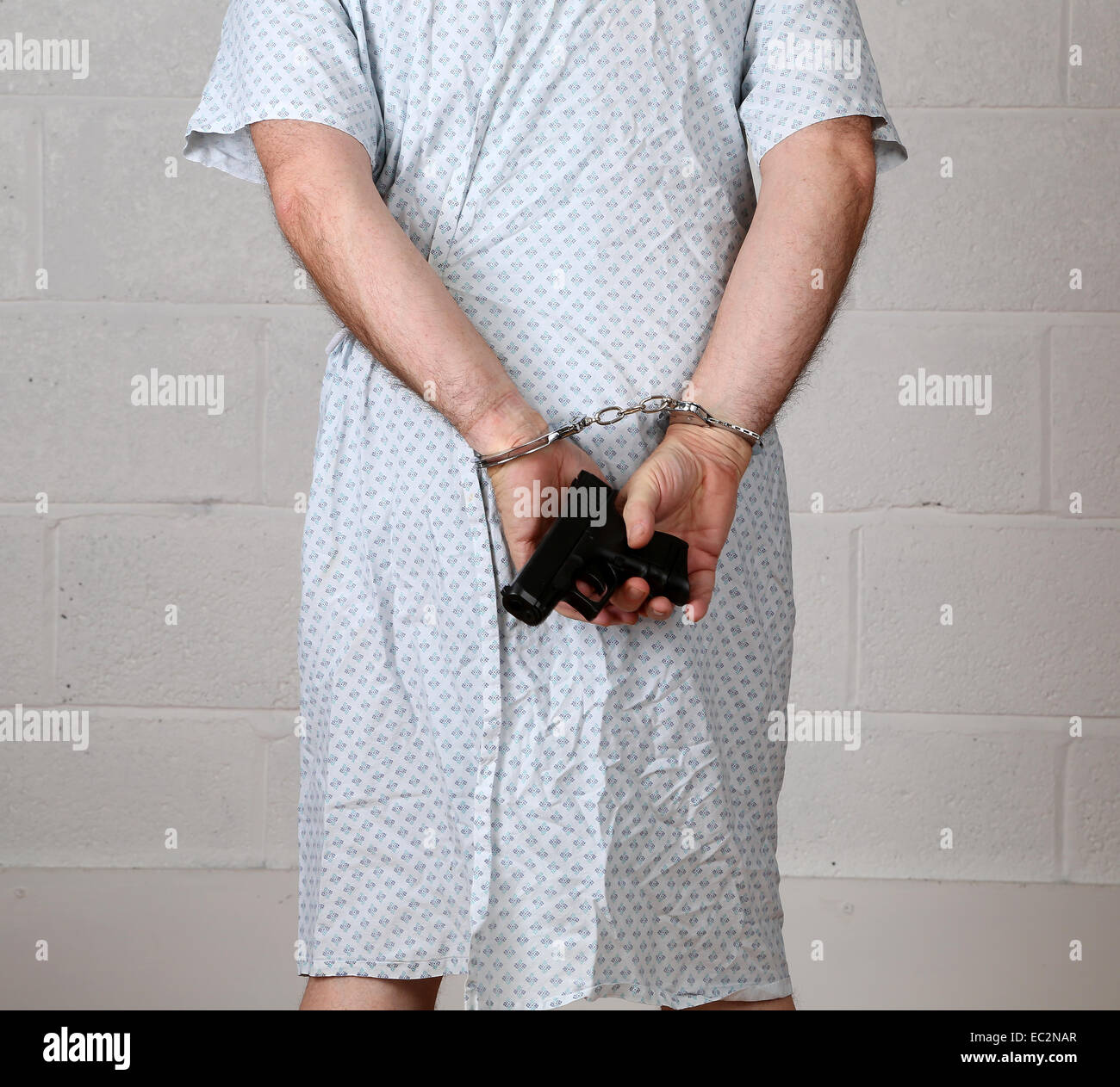 Ansicht von hinten von einem reifen Mann in ein Krankenhemd hält ein pistol.6th Dezember 2014 Stockfoto