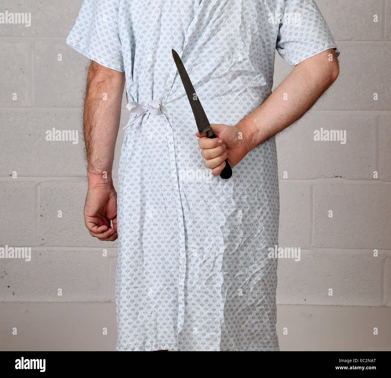 Ansicht von hinten von einem reifen Mann in ein Krankenhemd hält ein knife.6th Dezember 2014 Stockfoto