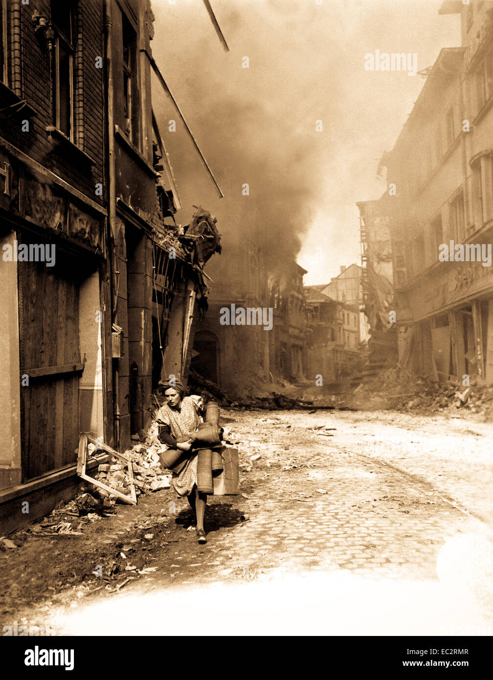 Deutsche Frau, die ein paar Besitztümer läuft von brennenden Gebäude in seigburg. Feuer begann durch die Nationalsozialisten saboteur. 13. april 1945. t4c Troy ein. Peters, USA. (Roberts Kommission) Stockfoto