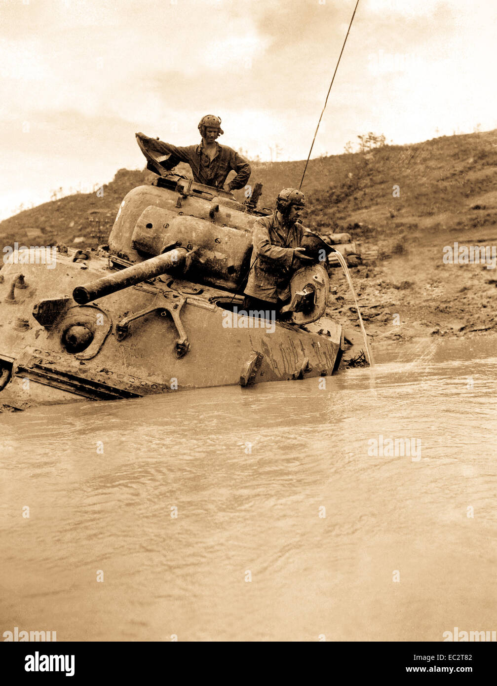 Ein Tank versenkt in 5 Fuß Wasser wartet zum Ziehen von Geräten. Der Kommandant gibt seinen Gefühlen vent, während sein Fahrer einen Helm verwendet, um das Innere zu Ballen. Okinawa, Mai 1945. Stockfoto