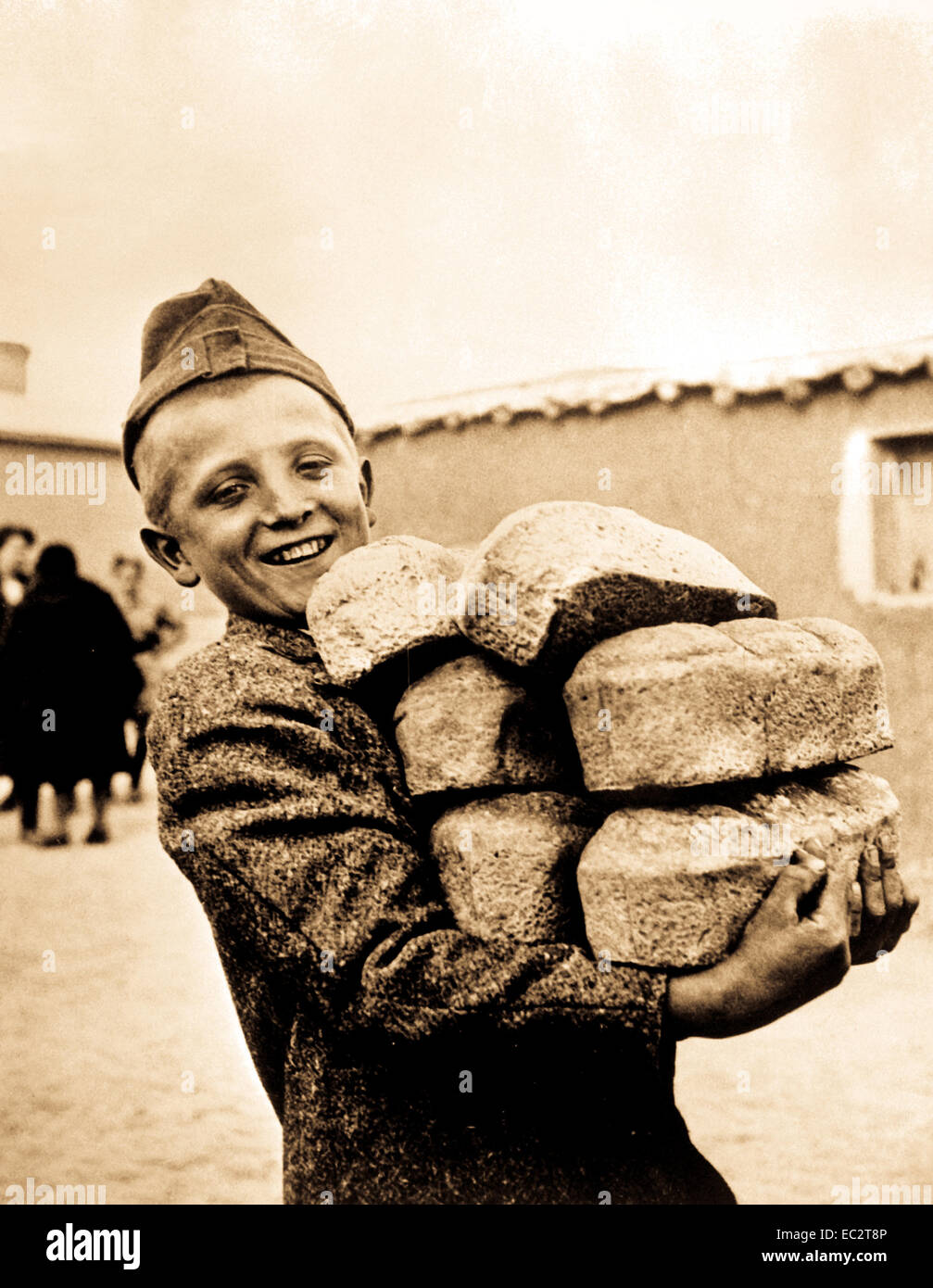 Polnischer Junge mit den Armen voll mit Brot aus Mehl, das vom amerikanischen Roten Kreuz geliefert wurde. Lächeln erwartet genug Brot zum Essen, etwas, das er nicht bekommen würde, wenn er um 1943 in seiner Heimat Polen, Russland, geblieben wäre. OWI. (Armee) Stockfoto