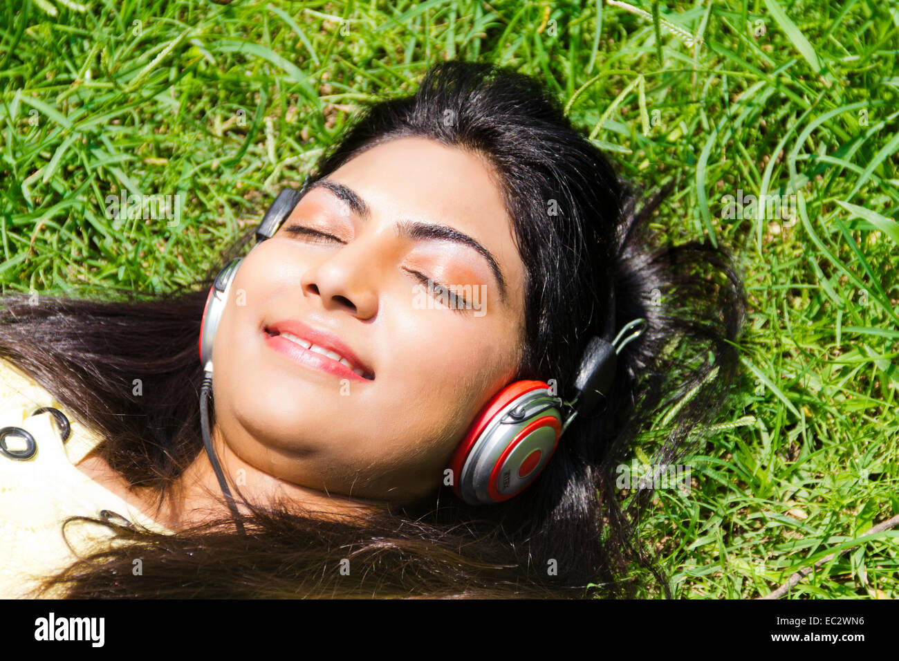 indische wunderschöne Dame Park hören von Musik Stockfoto
